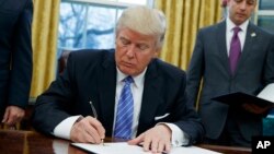 Donald Trump signe l'acte de retrait des Etats-Unis du traité de libre-échange transpacifique (TPP), dont l'administration de Barack Obama avait fait l'une de ses priorités, le 23 janvier 2017. (AP Photo/Evan Vucci, File)