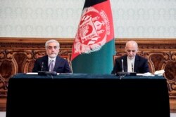 FILE - Afghan President Ashraf Ghani, right, and rival Abdullah Abdullah prepare to sign a power-sharing agreement at the Presidential Palace in Kabul, in this photograph taken May 17, 2020, and released by Afghanistan's Office of Chief Executive.