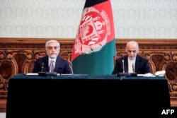 FILE - Afghan President Ashraf Ghani, right, and rival Abdullah Abdullah prepare to sign a power-sharing agreement at the Presidential Palace in Kabul, in this photograph taken May 17, 2020, and released by Afghanistan's Office of Chief Executive.