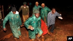 Les membres du Service national de la jeunesse emportent un cadavre dans une couverture au petit matin du 10 mai 2018 près de Solai, dans la vallée du Rift, au Kenya.