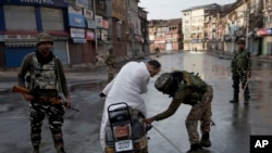 Tentara paramiliter India memeriksa bawaan seorang pria yang mengendarai skuter saat jam malam di Srinagar, wilayah Kashmir yang dikuasai India, Kamis, 8 Agustus 2019. 