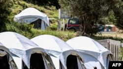 Security guards and members of medical staff stand by a temporary testing station for COVID-19 set up by a migrant and refugee camp, where cases were detected, on the Greek Mediterranean island of Lesbos on May 13, 2020.