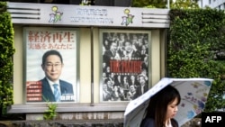 Una mujer se encuentra frente a carteles que muestran al primer ministro de Japón, Fumio Kishida (izq.), y a otro para las elecciones de liderazgo del Partido Liberal Democrático (PLD), afuera de la sede del partido en Tokio, el 27 de septiembre de 2024.