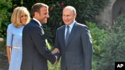 Presiden Perancis Emmanuel Macron (kanan) dan istrinya, Brigitte, menyambut Presiden Rusia Vladimir Putin di Bormes-les-Mimosas, selatan Perancis, 19 Agustus 2019. 