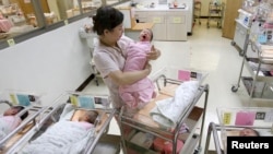 FILE - A nurse looks after babies inside the maternity ward of a hospital in Taipei, Oct. 25, 2011. 