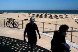 People walk at Carcavelos beach in Cascais, Portugal, July 8, 2021.