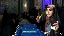 A woman flashes a victory sign with her inked finger while voting in parliamentary elections, at a polling station in Tehran, Iran, Feb. 21, 2020.