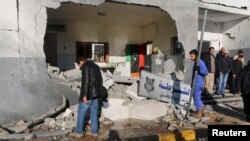 FILE - Civilians and security personnel stand at the scene of an explosion at a police station in Tripoli, Libya, a blast later claimed by militants professing loyalty to Islamic State, March 12, 2015. 