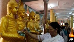 A local offers her money to the Buddha statue as praying during Khmer New Year on Monday, April 14, 2014, in downtown Phnom Penh, Cambodia. Throughout Cambodia, Khmers are holding ceremonies in preparation for the coming New Year's celebration which lasts for three days, from April 14 through 16 this year. (AP Photo/Heng Sinith)
