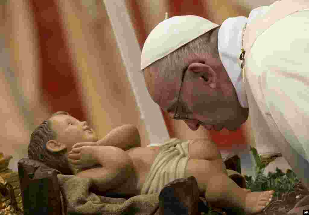 Pope Francis kisses the statue of Baby Jesus as he arrives to celebrate a Mass for families in St.Peter&#39;s Basilica at the Vatican.