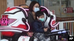 FILE - Visitors wear face masks to protect against the spread of the new coronavirus at Taipei Children's Amusement Park in Taipei, Taiwan, April 11, 2020. 