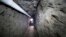 FILE - Federal Police officer stands in the tunnel where drug lord Joaquin "El Chapo" Guzman made his escape from the Altiplano maximum security prison in Almoloya, west of Mexico City, July 16, 2015.