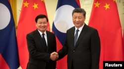 FILE - Laos' Prime Minister Thongloun Sisoulith and China's President Xi Jinping shake hands before a meeting at the Great Hall of the People in Beijing, China, Jan. 6, 2020.