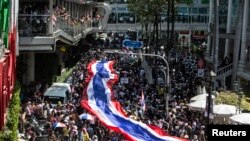 Demonstran anti-pemerintah berbaris membawa bendera Thailand raksasa di daerah perbelanjaan di pusat kota Bangkok (13/1). (Reuters/Nir Elias)