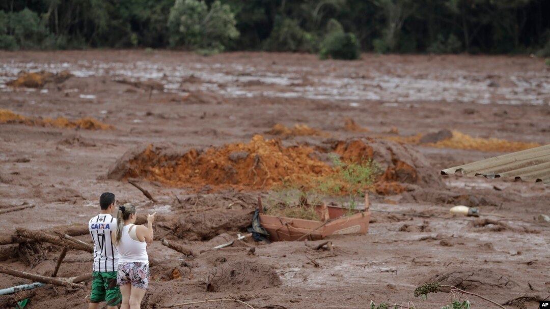 A couple with missing relatives look at the flooded area, after a dam collapsed in Brumadinho, Brazil, Jan. 26, 2019. An estimated 300 people were still missing and authorities expected the death toll to rise during a search made more challenging by rain.