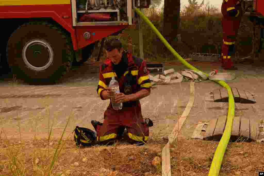 A firefighter from Slovakia cools himself down during a wildfire in Avgaria village on Evia island, about 184 kilometers (115 miles) north of Athens, Greece.