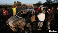 Relatives and civilians look at the wreckage of cars burned when a tanker crashed into several vehicles and killed several people, near the Rift Valley town of Naivasha, west of Kenya's capital, Nairobi, Dec. 11, 2016.