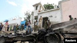 Security agents stand near the scene of a suicide bomb attack outside the United Nations compound in Somalia's capital Mogadishu, June 19, 2013. 