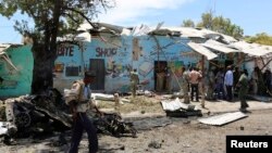 Seorang polisi berjalan di lokasi ledakan bom bunuh diri di dekat kedai teh di Mogadishu (27/2).