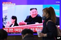 A woman passes by a TV screen showing an image of North Korean leader Kim Jong Un and his sister Kim Yo Jong during a news program at the Seoul Railway Station in Seoul, South Korea, Saturday, May 2, 2020.