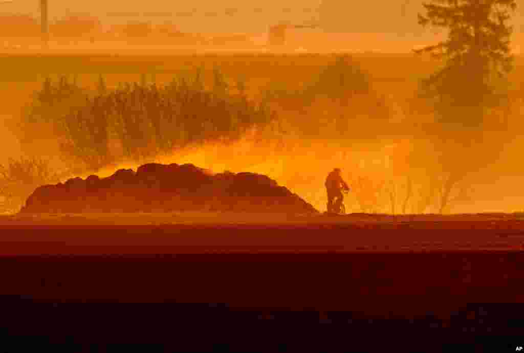 A man rides his bike past a steaming dunghill as the sun rises in Frankfurt, Germany.