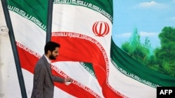 Seorang pria berjalan melewati mural bendera Iran di sebuah jalan di Teheran pada 26 Oktober 2024. (Foto: AFP)