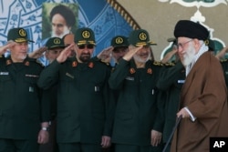 FILE- In this picture released by an official website of the office of the Iranian supreme leader, Supreme Leader Ayatollah Ali Khamenei, right, arrives at a graduation ceremony of the Revolutionary Guard's officers, in Tehran, Iran.