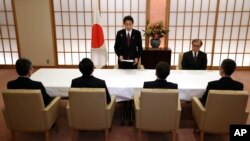 Japanese Foreign Minister Fumio Kishida, standing, gives instructions to members, foreground, of a newly-established international terrorism information collection unit at the Ministry of Foreign Affairs in Tokyo, Dec. 8, 2015.