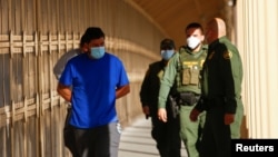 Di dân trong chương trình Thủ tục Bảo vệ Di dân (MPP), được cảnh sát Tuần tra Biên giới Hoa Kỳ áp tải qua Cầu Biên giới Quốc tế Lerdo Stanton để trả về Mexico từ Mỹ, ở El Paso, bang Texas, Mỹ, ngày 8 tháng 12, 2021.