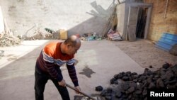 Un homme amasse du charbon qu'il utilise pour chauffer sa maison dans le village de Heqiaoxiang, province d'Hebei, Chine, le 5 décembre 2017.