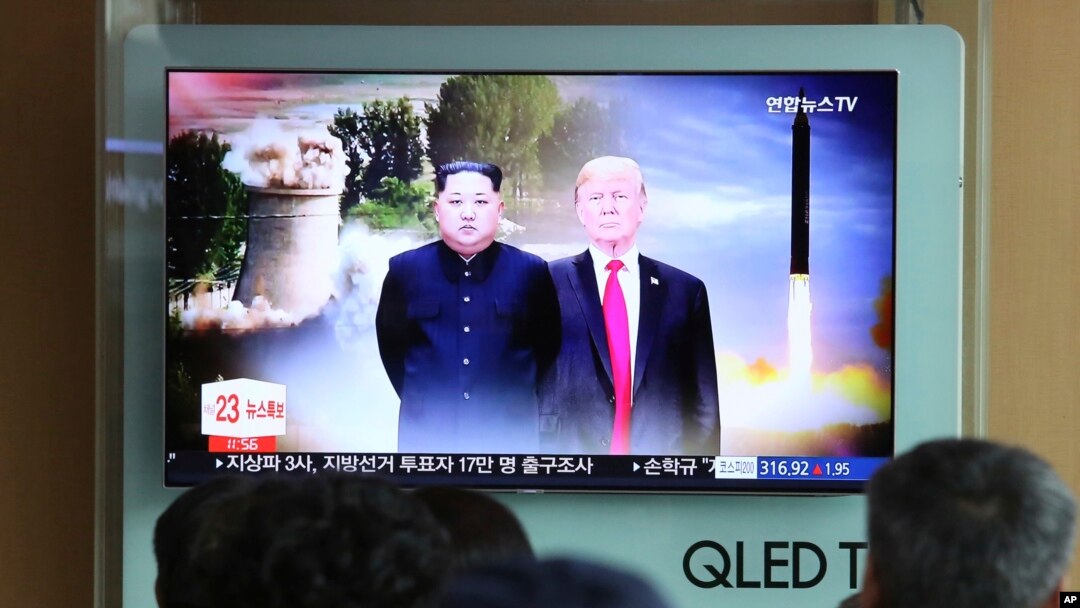 
Warga menyaksikan siaran TV yang menampilkan gambar Presiden AS Donald Trump (kanan) dan Pemimpin Korut Kim Jong Un.