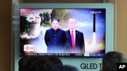 FILE - People watch a TV screen showing file footage of U.S. President Donald Trump, right, and North Korean leader Kim Jong Un.