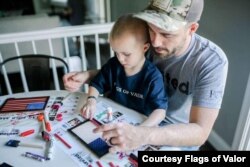 A father and son work together on a children’s flag kit from Flags of Valor in Ashburn, Virginia. (Photo courtesy Flags of Valor)
