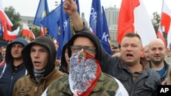 FILE - Protesters shout anti-migrant slogans as several thousand right-wing nationalists rally, demonstrating against EU proposed quotas for Poland to spread the human tide of refugees around Europe, in Warsaw, Poland, Sept. 12, 2015.