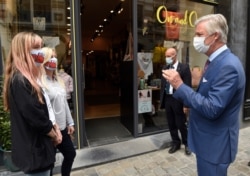 Belgium's King Philippe, right, wearing a mouth mask, speaks with shopkeepers in Brussels, Sunday, May 10, 2020.