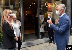 Belgium's King Philippe, right, wearing a mouth mask, speaks with shopkeepers in Brussels, Sunday, May 10, 2020.