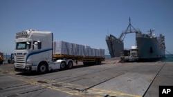 U.S. Army soldiers stand next to arriving trucks loaded with humanitarian aid at the U.S.-built floating pier before reaching the beach on the coast of the Gaza Strip, June 25, 2024. The pier was removed on June 28 due to weather, and it is unknown whether it will be reinstalled.
