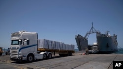ARCHIVO: Soldados estadounidenses junto a camiones cargados con ayuda humanitaria en el muelle flotante construido por EEUU frente a la costa de la Franja de Gaza, el 25 de junio de 2024.