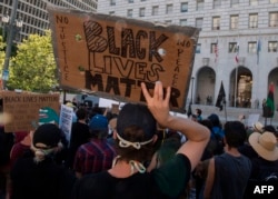Supporters of Black Lives Matter hold signs during a protest outside the Hall of Justice as they demonstrate against the death of George Floyd, in Los Angeles, California, on June 10, 2020.