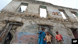 Internally displaced children stand outside a decrepit building they are using as a temporary home in the Hodan district of Somalia's capital Mogadishu