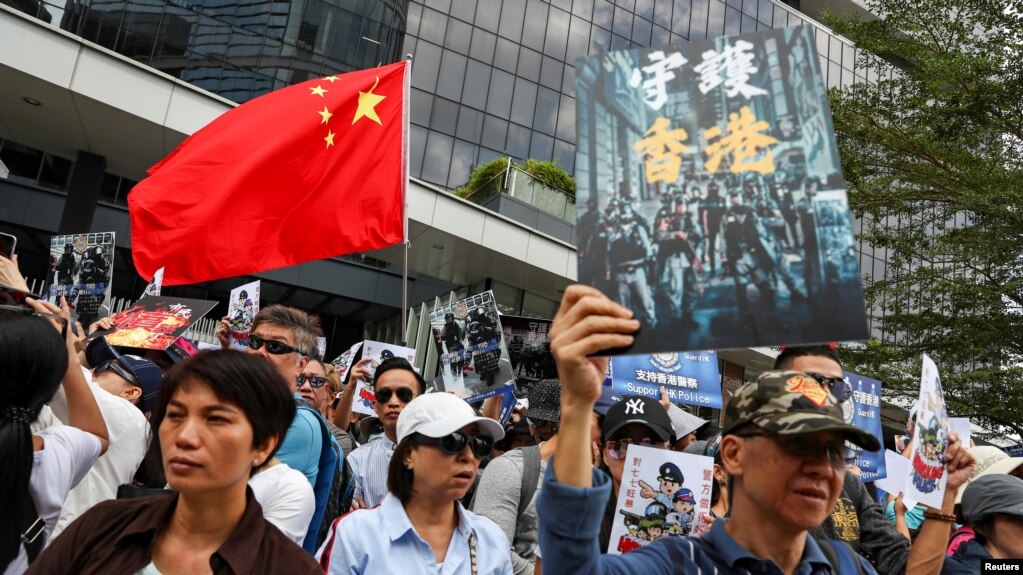 People hold a China national flag and signs as they participate in a pro-government rally to show their support for the police and government in Hong Kong.