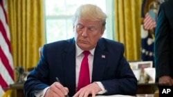 FILE - President Donald Trump signs an executive order in the Oval Office of the White House, in Washington, June 24, 2019.