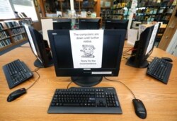 FILE - In this Aug. 22, 2019, file photo, signs on a bank of computers tell visitors that the machines are not working at the public library in Wilmer, Texas. Twenty-two local governments in Texas were hit by ransomware in August 2019.