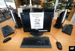 FILE - In this Aug. 22, 2019, file photo, signs on a bank of computers tell visitors that the machines are not working at the public library in Wilmer, Texas. Twenty-two local governments in Texas were hit by ransomware in August 2019.