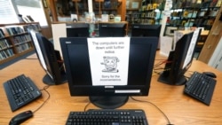 FILE - In this Aug. 22, 2019, photo, signs on a bank of computers tell visitors that the machines are not working at the public library in Wilmer, Texas.