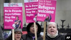 Stand Up To Racism campaigners hold banners outside the High Court in London, Dec. 19, 2022. 