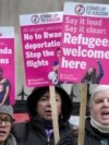 FILE - Campaigners hold signs outside the High Court in London, Dec. 19, 2022, protesting United Kingdom's controversial plan to deport some asylum-seekers to Rwanda. A UK official arrived in Rwanda on Saturday to reinforce the UK government's commitment to the plan.