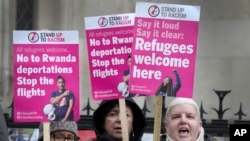 FILE - Campaigners hold signs outside the High Court in London, Dec. 19, 2022, protesting United Kingdom's controversial plan to deport some asylum-seekers to Rwanda. A UK official arrived in Rwanda on Saturday to reinforce the UK government's commitment to the plan.