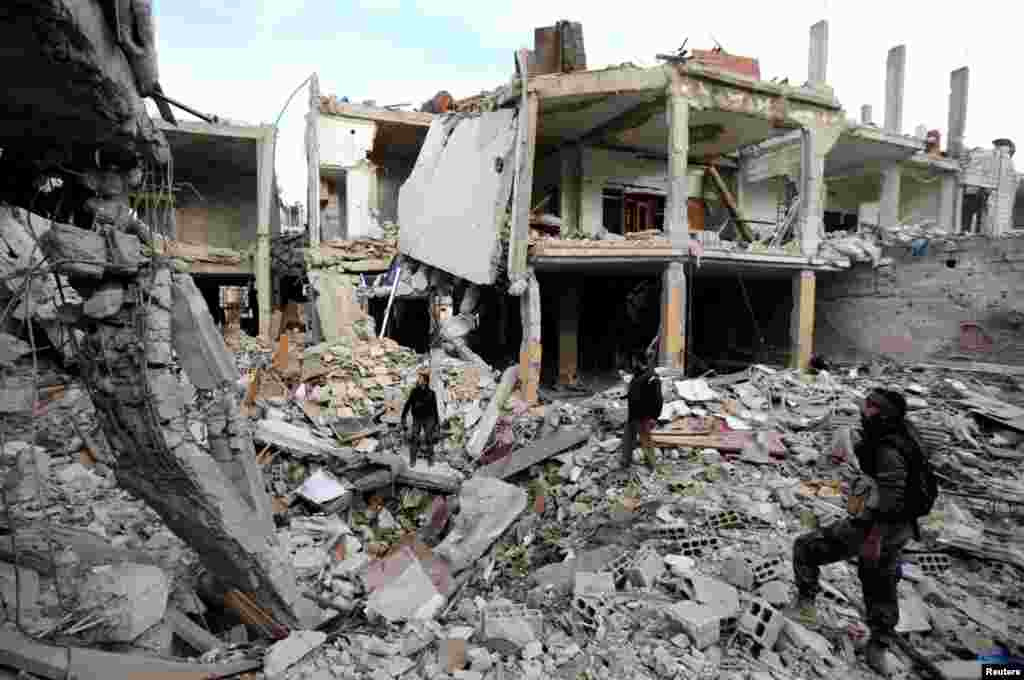 Free Syrian Army fighters walk in the rubble of buildings destroyed by Syrian Army air strikes in the Arabeen neighborhood of Damascus, January 24, 2013.