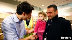 Syrian refugees are greeted by Canada's Prime Minister Justin Trudeau (L) on their arrival from Beirut at the Toronto Pearson International Airport in Mississauga, Ontario, Canada, Dec. 11, 2015.